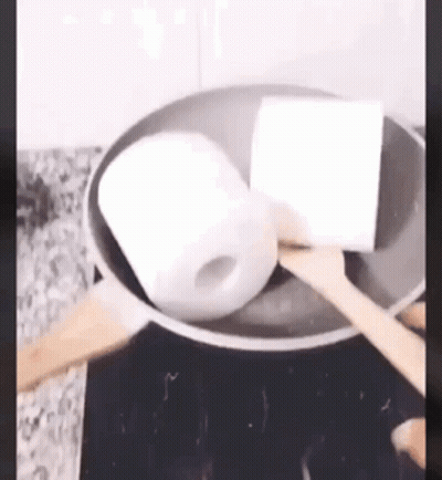 Toilet Paper Being Cooked In Frying Pan With Wooden Spoon GIF