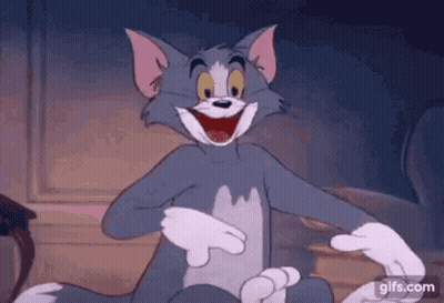 Tom From The Cartoon Tom And Jerry Is Laughing While Sitting On A Couch . GIF