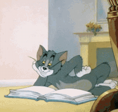 Tom From Tom And Jerry Is Laying On The Floor Reading A Book GIF