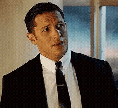 Tom Hardy Is Wearing A Suit And Tie And Looking At The Camera . GIF