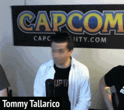 Tommy Tallarico Is Standing In Front Of A Large Capcom Sign GIF