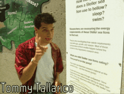 Tommy Tallarico Standing In Front Of Large Poster GIF