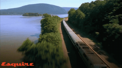 Train Going Down Tracks Next To Water With Esquire GIF