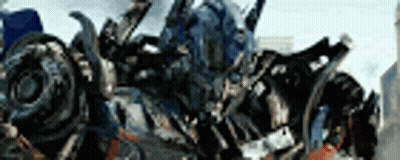 Transformer Standing In Front Of Blurry City GIF