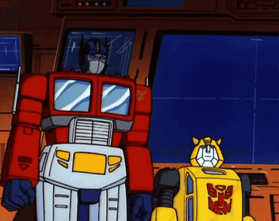 Transformers Optimus Prime And Bumblebee Standing Next To Each Other GIF