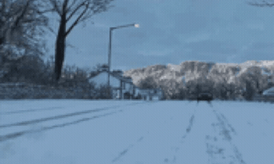 Truck Driving Down Snowy Street GIF
