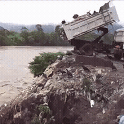 Truck On Pile Of Rocks Near River GIF