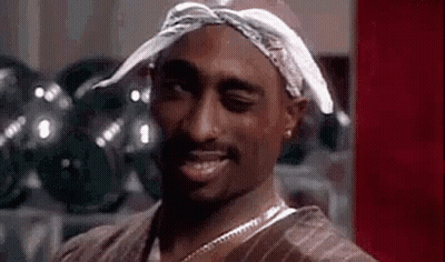 Tupac Shakur Is Wearing A Bandana On His Head And Smiling . GIF