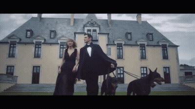 Tuxedo Man And Black Dress Woman Walking Two Dogs GIF