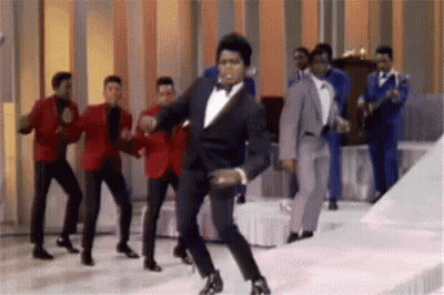 Tuxedo Man Dancing With Other Men On Stage GIF