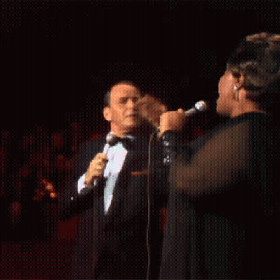 Tuxedo Man Sings To Woman In Black Dress GIF