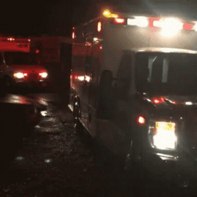 Two Ambulances Parked Next To Each Other In Dark GIF