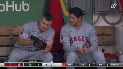 Two Angels Baseball Players Sit On A Bench Looking At A Tablet GIF