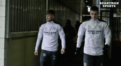 Two Athletes Wearing Marathon Shirts Walk Down A Hallway GIF