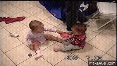 Two Babies Are Sitting On A Tiled Floor Playing With Toys . GIF