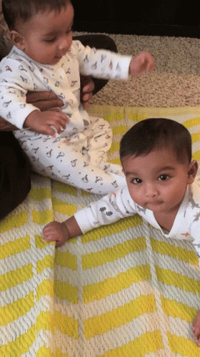 Two Baby Boys Laying On Yellow And White Blanket GIF