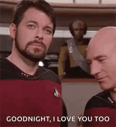 Two Bald Bearded Men Talking On Ship GIF