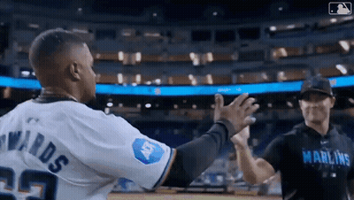 Two Baseball Players Are Giving Each Other A High Five On A Field . GIF