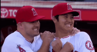 Two Baseball Players Are Hugging Each Other And Smiling In The Dugout . GIF