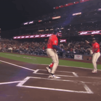 Two Baseball Players Are Jumping In The Air On A Field With A Sign That Says Get Water In The Background GIF