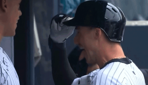 Two Baseball Players Are Standing Next To Each Other And One Is Wearing A Black Helmet . GIF