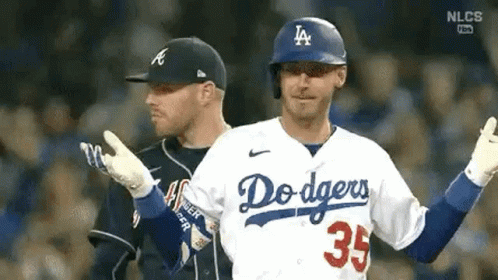 Two Baseball Players Are Standing Next To Each Other On A Field . One Of The Players Is Wearing A Dodgers Jersey . GIF