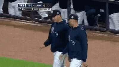 Two Baseball Players Are Walking On A Field With A Scoreboard Behind Them That Says Yes GIF