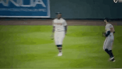 Two Baseball Players Are Walking On A Field . GIF