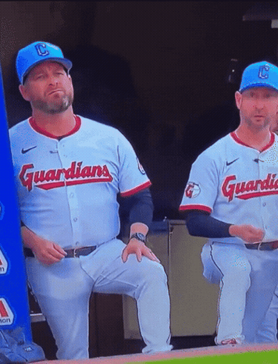Two Baseball Players In Guardians Uniforms Sitting On Dugout GIF