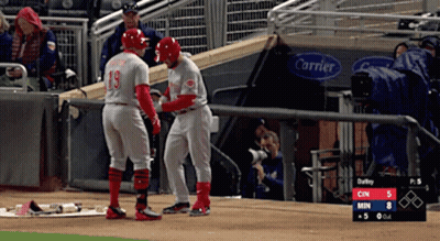 Two Baseball Players Standing On A Field With A Carrier Sign Behind Them GIF