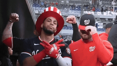 Two Baseball Players Wearing Hats And Gloves Are Posing For A Picture In A Stadium . GIF