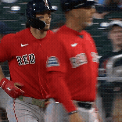 Two Baseball Players Wearing Red Jerseys Are Walking On A Field GIF