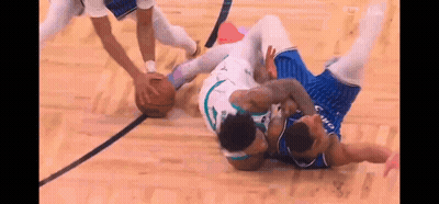Two Basketball Players Are Fighting For The Ball On A Court During A Game . GIF