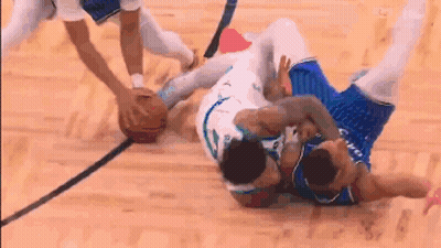 Two Basketball Players Are Fighting Over A Basketball On A Wooden Court . GIF