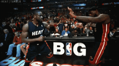 Two Basketball Players Are Giving Each Other A High Five In Front Of A Sign That Says Big GIF