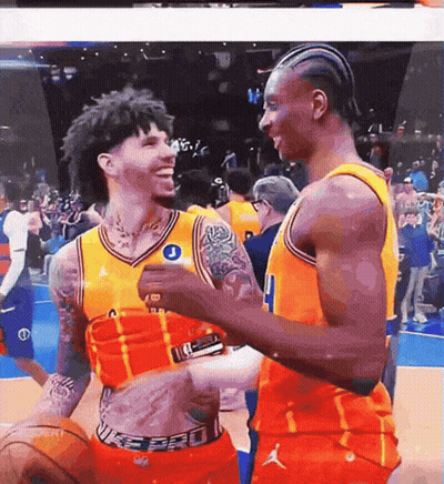 two basketball players are hugging and one has a tattoo on his chest that says j.