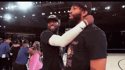 Two Basketball Players Are Hugging Each Other On A Basketball Court GIF
