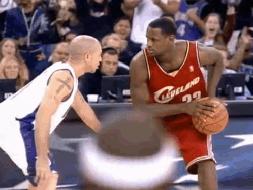 Two Basketball Players Are Playing A Game Of Basketball And One Of Them Is Wearing A Red Cleveland Jersey . GIF