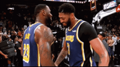 Two Basketball Players Are Shaking Hands During A Game In Front Of A Crowd . GIF