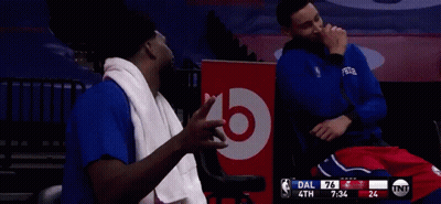 Two Basketball Players Are Sitting In Front Of A Bose Sign GIF