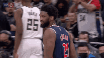 Two Basketball Players Are Standing Next To Each Other In A Stadium . GIF