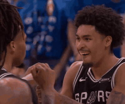 Two Basketball Players Are Talking To Each Other In Front Of A Crowd With A Sign That Says Cest On It GIF