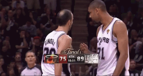 Two Basketball Players Shake Hands In Front Of A Scoreboard That Says The Finals On It GIF