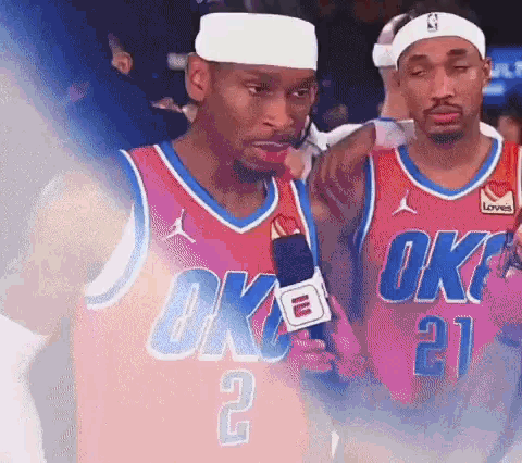 Two Basketball Players Wearing Oklahoma City Thunder Jerseys Are Talking Into Microphones . GIF