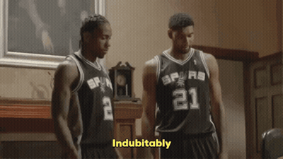 Two Basketball Players Wearing Spurs Jerseys Stand In A Room GIF