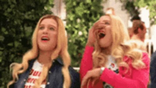 Two Blonde Women Are Laughing And Covering Their Faces . GIF