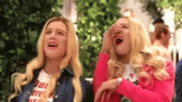 Two Blonde Women Are Laughing And Covering Their Faces . GIF