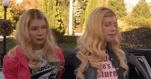 Two Blonde Women Are Sitting Next To Each Other In A Car And Making Funny Faces . GIF