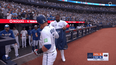 Two Blue Jays Baseball Players In Front Of Rogers Banner GIF