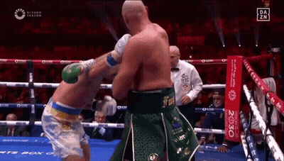 Two Boxers Are Fighting In A Boxing Ring While A Referee Looks On . GIF